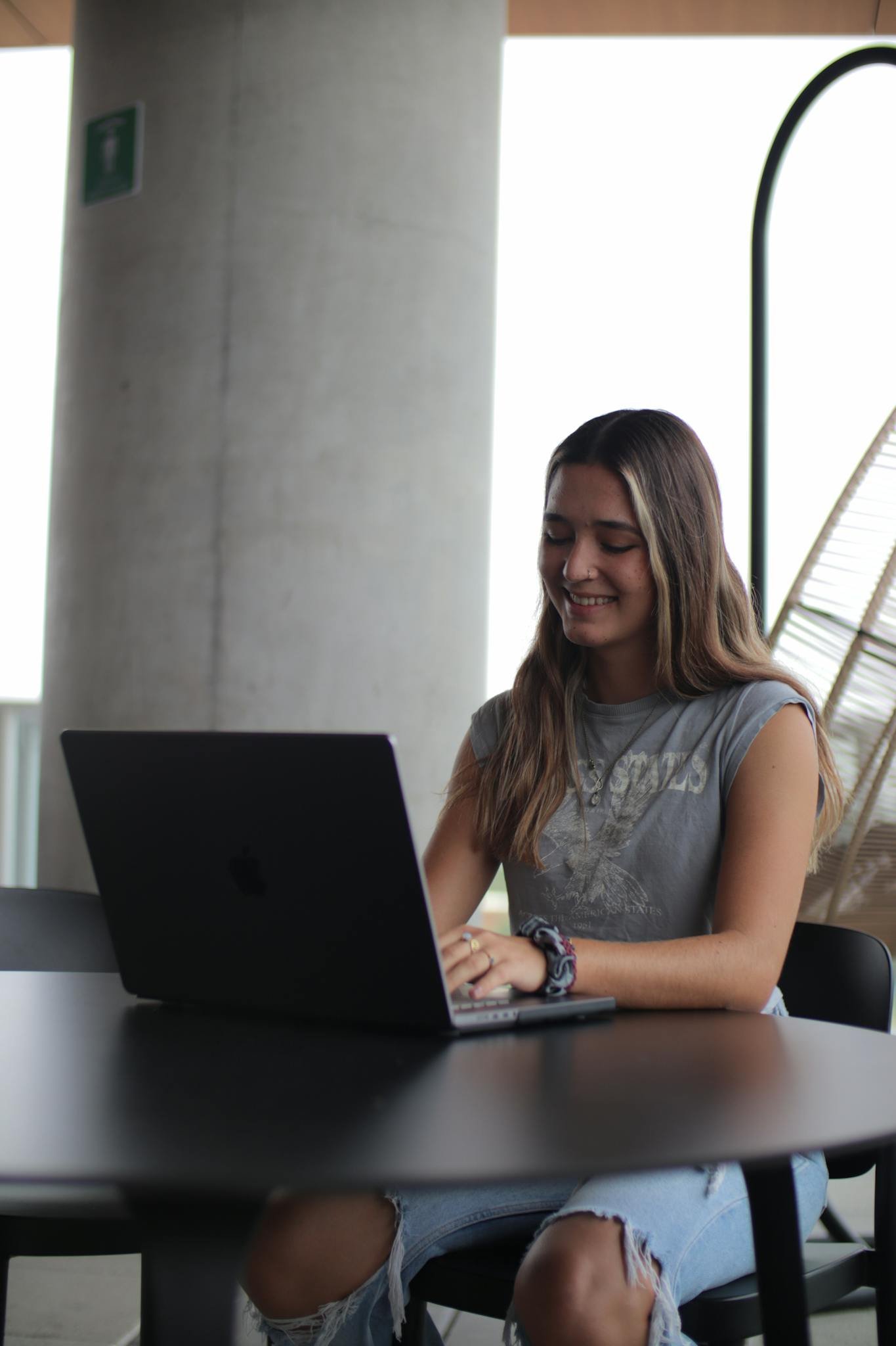 Young woman using a laptop in a modern indoor setting, focused on online study.