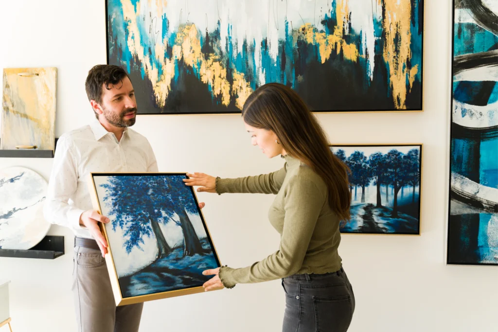 Mujer mirando un cuadro que le enseña el encargado de la galería