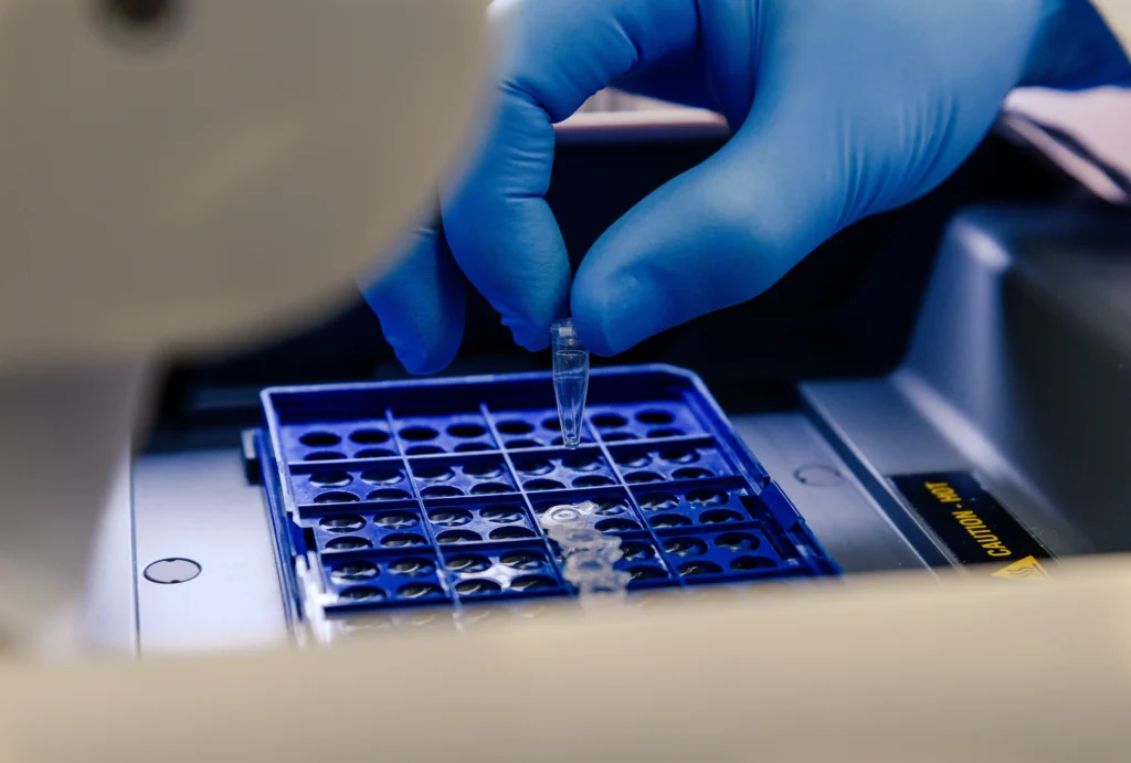 Persona colocando microtubo en un equipo de laboratorio