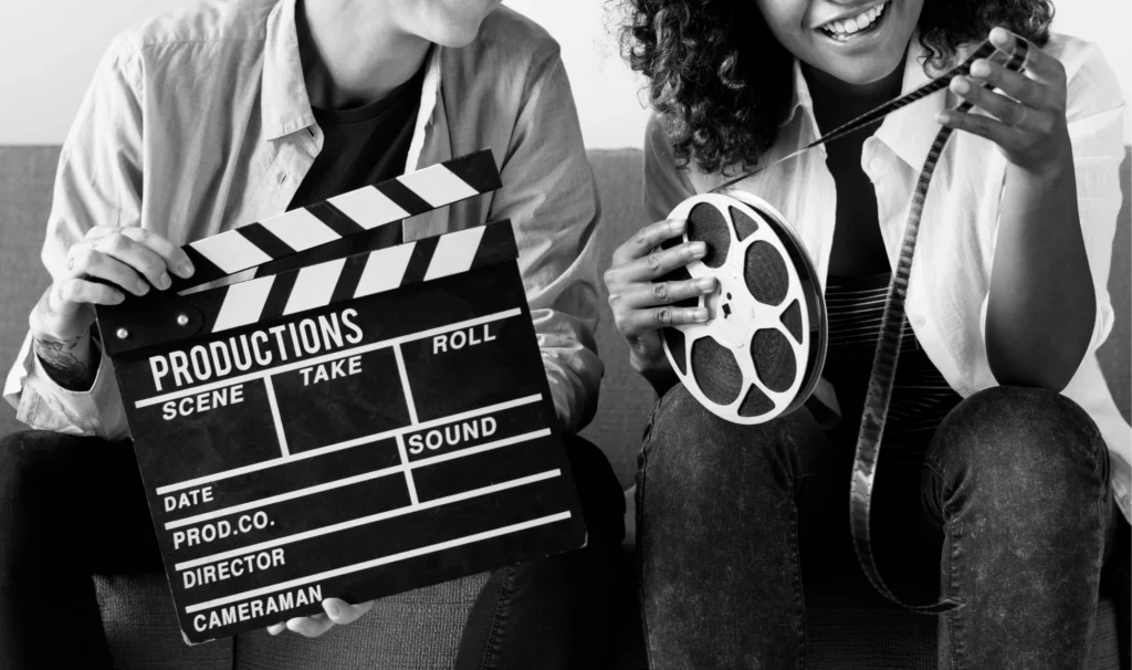 Hombre y mujer con claqueta y cinta de cine en sus manos
