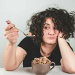 Mujer preocupada mirando una cuchara con cereales