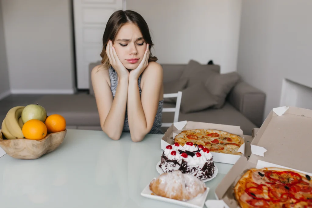 Mujer sentada mirando a mucha cantidad de comida