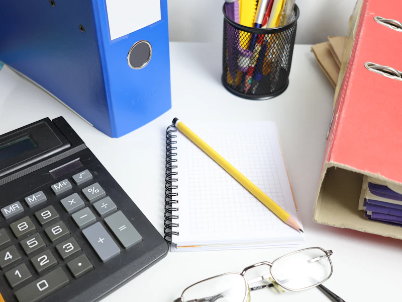 Carpetas y cuadernos ordenados sobre una mesa junto a una calculadora