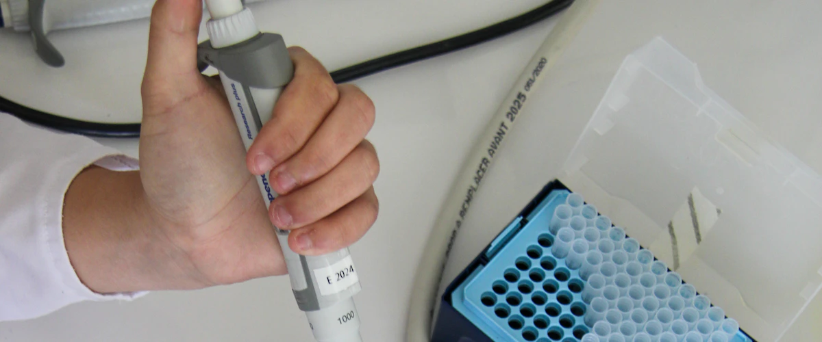 Científico utilizando micropipeta para preparar muestras de investigación molecular