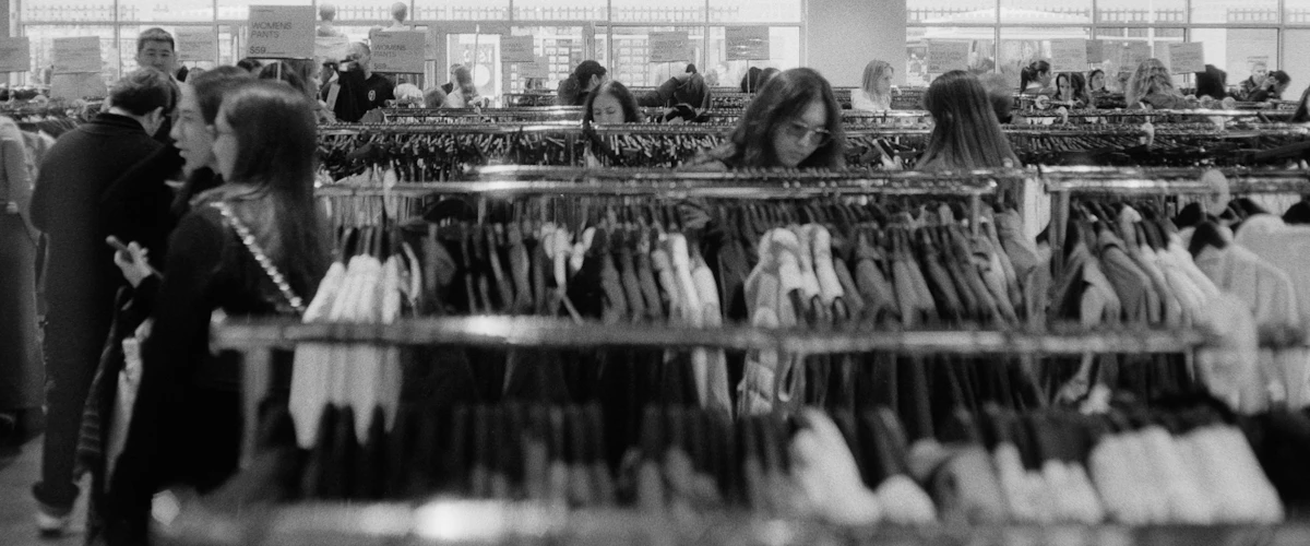 Clientes observando prendas expuestas en percheros de una tienda luminosa