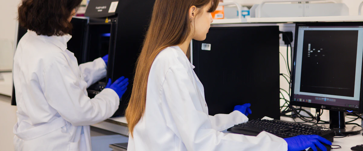 Dos investigadores analizando datos biológicos en ordenadores del laboratorio