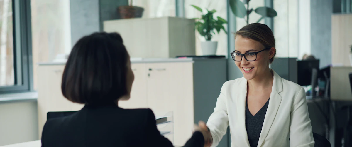 Dos profesionales estrechan sus manos tras conversar en una entrevista laboral