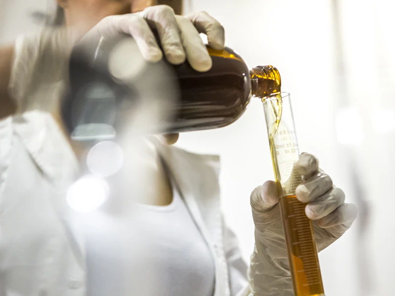 Especialista con bata blanca examina una muestra cosmética en un laboratorio luminoso