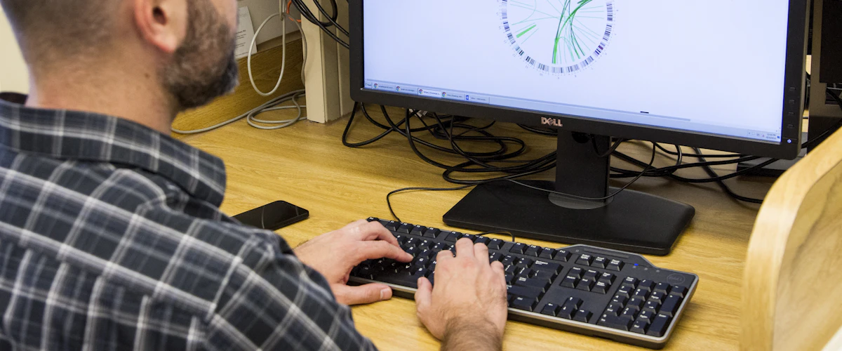 Especialista revisando resultados genómicos en una pantalla dentro de laboratorio