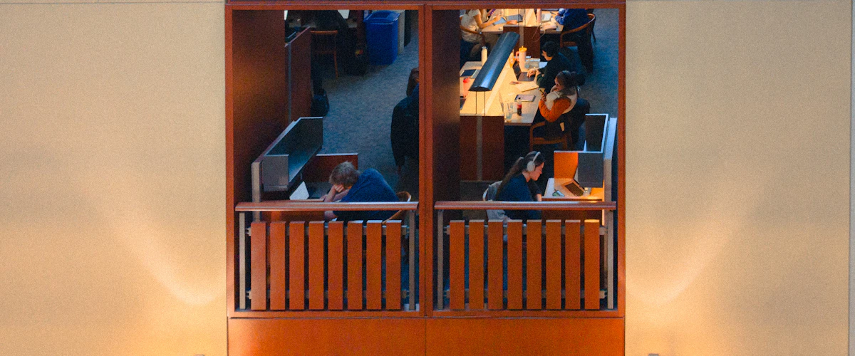 Estudiantes con portátiles en puestos individuales de una biblioteca universitaria