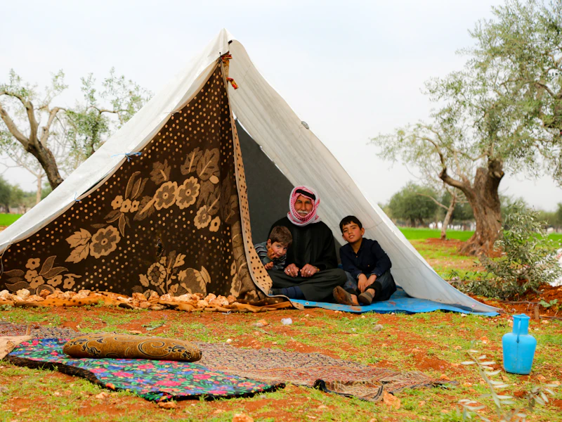 Familias desplazadas descansando ante un refugio provisional durante una crisis