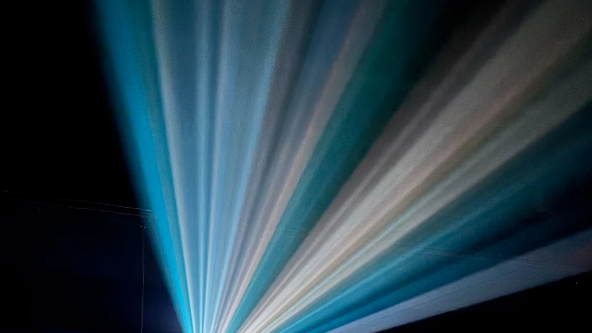 Haces de luz de un proyector atraviesan una sala de cine vacía