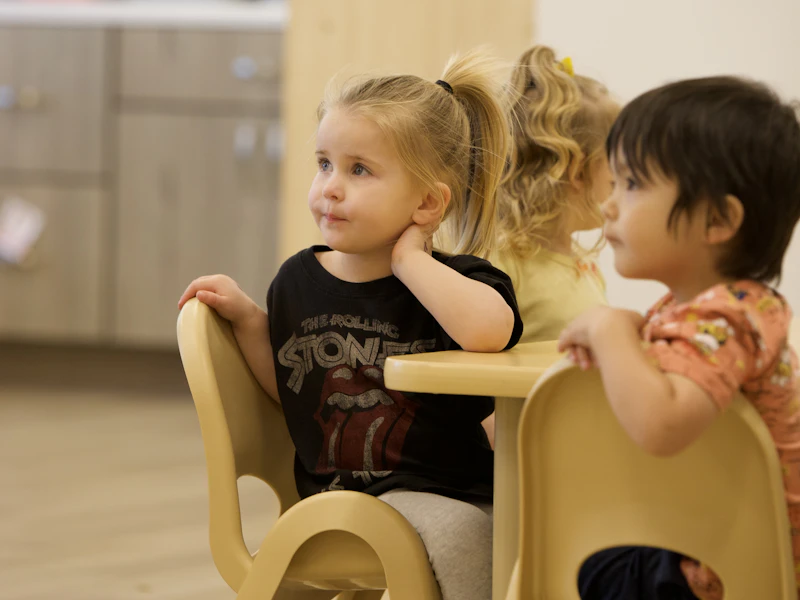Niños pequeños escuchan atentos alrededor de una mesa durante una actividad escolar