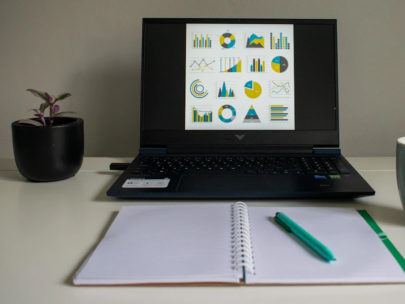 Ordenador con gráficos junto a un cuaderno en una mesa de trabajo