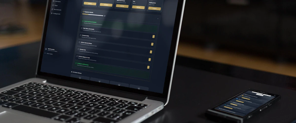 Ordenador portátil y móvil mostrando interfaces digitales en un escritorio