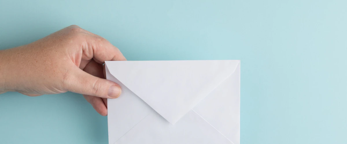 Persona muestra un sobre blanco como símbolo de un correo de bienvenida