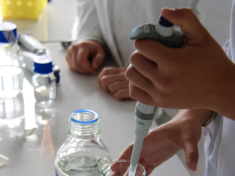 Técnico de laboratorio utilizando una micropipeta junto a material de vidrio