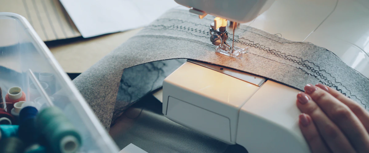 Una máquina de coser realiza una costura junto a hilos de colores