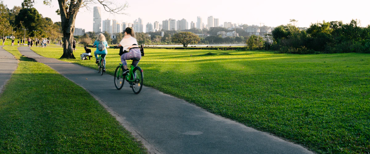 Varias personas recorren en bicicleta un sendero de un parque soleado